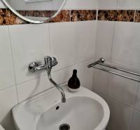 Waschbecken in einem Einfamilienhaus mit rundem Spiegel und Fliesen mit braunem Muster.