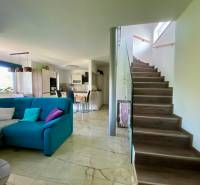 Wohnzimmer mit Küche in einem Einfamilienhaus, Treppe, bequeme Couch und Esstisch.
