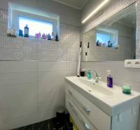 Badezimmer in einem Einfamilienhaus mit Waschbecken, Spiegel und viel Kosmetik.