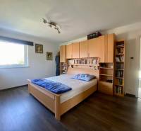 Schlafzimmer mit Bett, Holzmöbeln und Bücherregal in einem Einfamilienhaus.