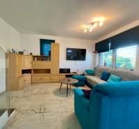 Wohnzimmer mit hellem Boden, Holzschrank und blauem Sofa in einem Einfamilienhaus.