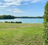 Ein ruhiger Wasserbereich bei einem Einfamilienhaus in Vojka nad Dunajom mit Grünflächen und einem Sonnenschirm.