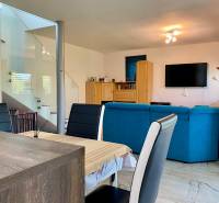 Wohnzimmer in einem Einfamilienhaus mit einem blauen Sofa, einem Esstisch und einem Fernseher an der Wand.