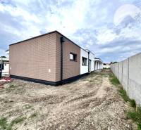 Ein Einfamilienhaus in Miloslavov mit einer Ziegelfassade und einem Grundstück neben einem Betonzaun.