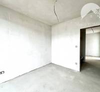 Unvollendetes Zimmer in einem Einfamilienhaus mit weißen Wänden und Betonboden.