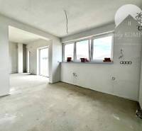 Ein leerer Raum in einem Einfamilienhaus mit drei großen Fenstern und einem Betonboden.