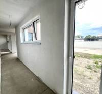 Flur mit Fenstern und Eingang in einem Einfamilienhaus. Auf dem Boden ist Beton.