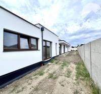 Ein Einfamilienhaus in Miloslavov mit weißer Fassade, daneben steht ein Zaun und eine Straße.