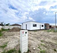 Baugrundstück neben einem Einfamilienhaus in Miloslavov mit sichtbarem Stromverteiler und Betonzaun.