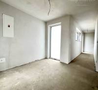 Ein Flur in einem Einfamilienhaus mit unverputzten Wänden und nacktem Boden.