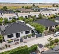 Ein Einfamilienhaus in der Feniklová-Straße in Malinovo mit Solarpanelen und Garten.