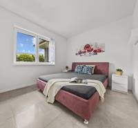 Schlafzimmer im Einfamilienhaus mit Doppelbett, Blumenbild und Nachttischen.
