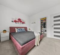 Schlafzimmer mit Einbauschrank, Bett und Dekoration mit roten Blumen in einem Einfamilienhaus.