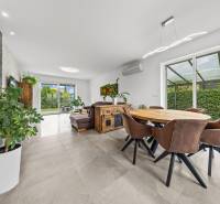 Innenraum eines Einfamilienhauses mit Essecke, Ledersesseln und Blick in den Garten.
