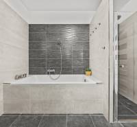 Graues Badezimmer mit Badewanne und Dusche in einem Einfamilienhaus.