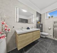 Badezimmer mit Doppelwaschbecken und Blumendekoration in einem Einfamilienhaus.