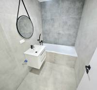 Badezimmer in einer 3-Zimmer-Wohnung mit Badewanne, Waschbecken und Spiegel an der Wand.