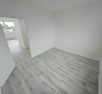 Ein heller Raum in einer 3-Zimmer-Wohnung mit Laminatboden und offenen Türen.