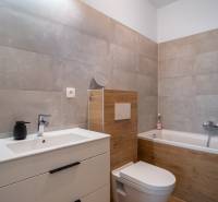 Ein Badezimmer in einem Einfamilienhaus mit Badewanne, Waschbecken und Toilette in neutralen Tönen.