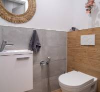 Badezimmer in einem Einfamilienhaus mit Waschbecken, Spiegel und Toilette.