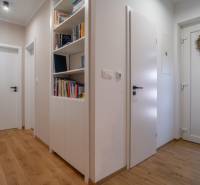 Der Flur eines Einfamilienhauses mit Bücherregalen, Holzboden und verzierten Türen.