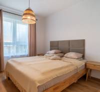 Spálňa v rodinnom dome s drevenou posteľou a nočným stolíkom.