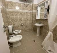 Badezimmer in einer Ferienwohnung; Waschbecken, Spiegel, Toilette, Bidet und Wassererhitzer.
