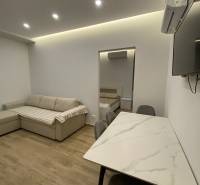 Wohnbereich eines Ferienapartments mit Sofa, Esstisch und Zugang zum Schlafzimmer.