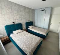 Doppelzimmer mit blauen Betten und gemusterter Wand im Ferienapartment.