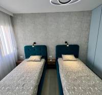 Doppelzimmer mit geometrischer Tapete und moderner Beleuchtung in einer Ferienwohnung.
