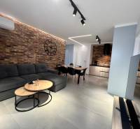 Wohnzimmer in einer Ferienwohnung mit Ziegelwand, Sofa und Fernseher.