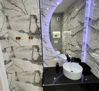 Badezimmer in der Ferienwohnung mit rundem Spiegel und eleganten Fliesen.