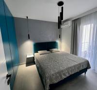 Ein Zimmer mit einem bequemen Bett, einem Schrank, Vorhängen und Balkontüren.