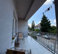 Der Balkon eines Einfamilienhauses in Komárno mit Blick auf die Straße mit parkenden Autos und Bäumen.