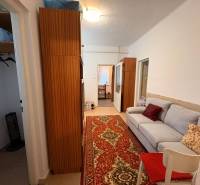 Ein Flur in einem Einfamilienhaus mit einem Sofa, einem Holzschrank und einem roten Teppich.