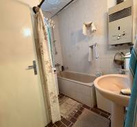 Ein Badezimmer in einem Einfamilienhaus mit einer Badewanne, einem Gasheizer und einem gefliesten Boden.