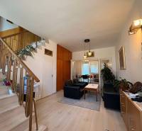 Wohnzimmer mit Treppe in einem Einfamilienhaus, mit Sitzgelegenheit und dekorativen Elementen.