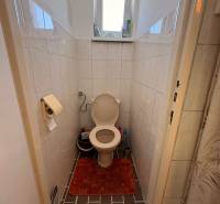 Badezimmer eines Einfamilienhauses mit Toilette, Fliesen und kleinem Fenster.
