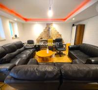 Wohnzimmer in einem Einfamilienhaus mit schwarzen Sofas und einer Steinwand.