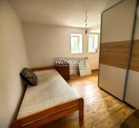 Ein Zimmer mit einem Einzelbett, einem Schrank und zwei Fenstern in einem Einfamilienhaus.