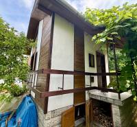 Ein Ferienhaus in Mojša mit Holzelementen, umgeben von Grün und Bäumen.