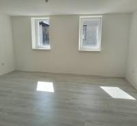 Ein heller Raum mit zwei Fenstern und Laminatboden in einem Einfamilienhaus.