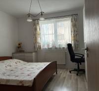 Schlafzimmer mit Bett, Arbeitsstuhl und Kommode in einem Einfamilienhaus.