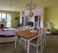 Wohnzimmer in einem Einfamilienhaus, helle Wände, großes lila Sofa, Esstisch.