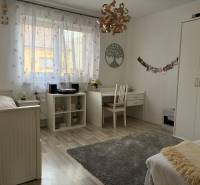 Helles Zimmer in einem Einfamilienhaus mit weißen Möbeln, Schreibtisch und Dekorationen.