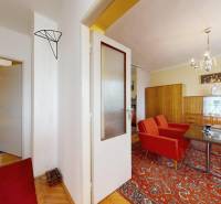 Wohnzimmer und Schlafzimmer in einem Einfamilienhaus mit Retro-Möbeln und einem rot-orangefarbenen Teppich.