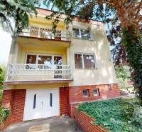 Ein Einfamilienhaus in der Božena Němcová Straße in Komárno, umgeben von Bäumen und Kletterpflanzen.
