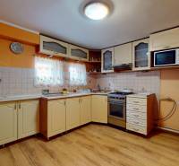 Eine Küche in einem Einfamilienhaus mit hellen Schränken, Holzboden und orangefarbenen Wänden.