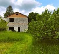 Ein Einfamilienhaus in Čelovce mit Garten und Bäumen, umgeben von grüner Natur und Himmel.