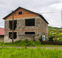 Unvollendetes Einfamilienhaus in Čelovce mit grasbewachsener Umgebung und Nebengebäude.